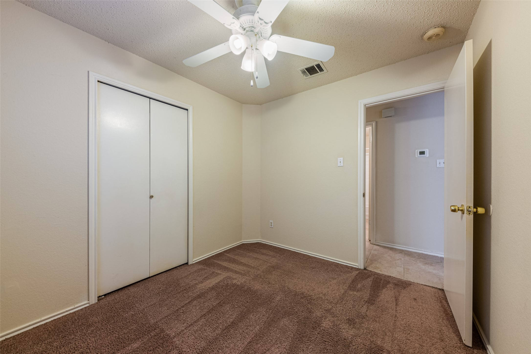7216 Aldea Drive, Unit A Austin, TX 78745 - Photo 16 of 25 Interior room featuring neutral wall paint, brown carpet flooring, and a white ceiling fan with integrated lighting