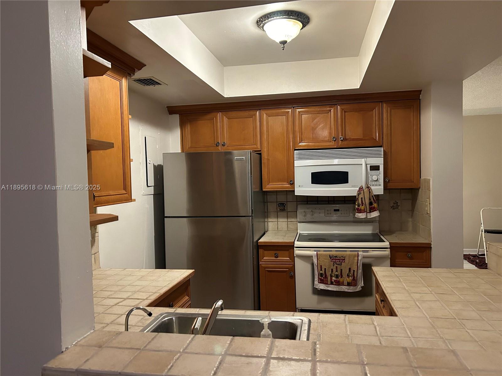 9411 Southwest 4th Street, Unit 202 Miami, FL 33174 - Photo 6 of 20 a kitchen with a refrigerator a stove top oven a sink and cabinets