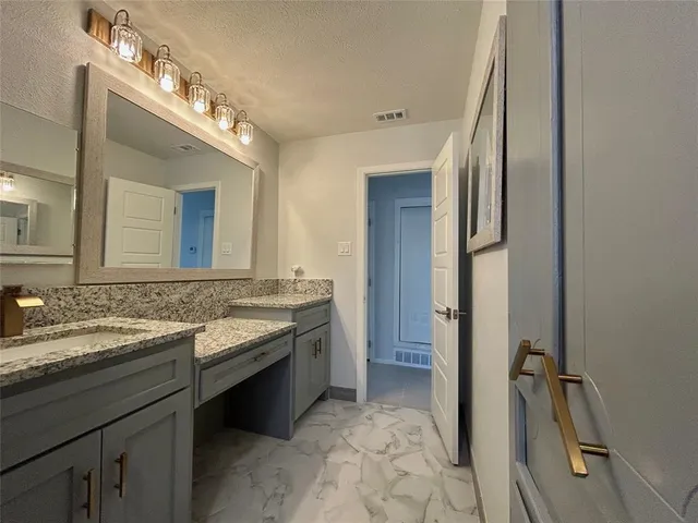 a bathroom with a granite countertop sink a mirror and a bathtub