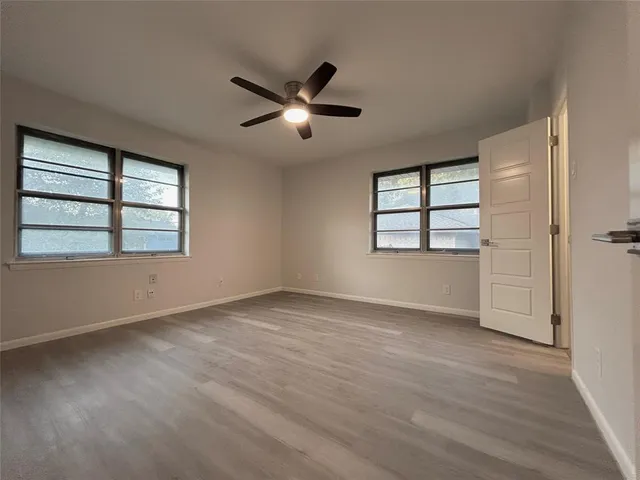 a view of empty room with wooden floor and fan