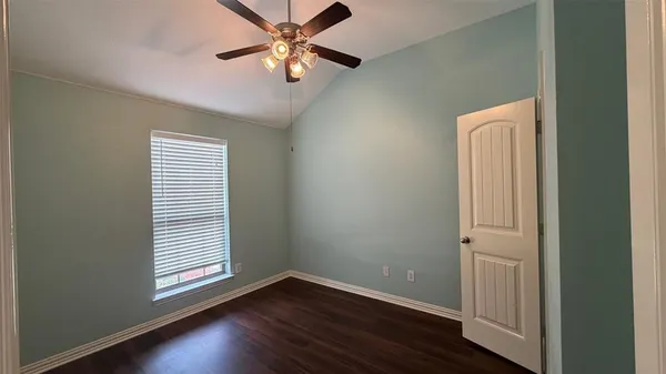 an empty room with wooden floor closet and windows