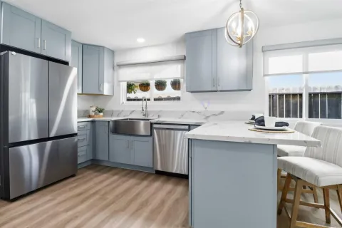 a kitchen with stainless steel appliances a sink a stove a refrigerator cabinets and a window