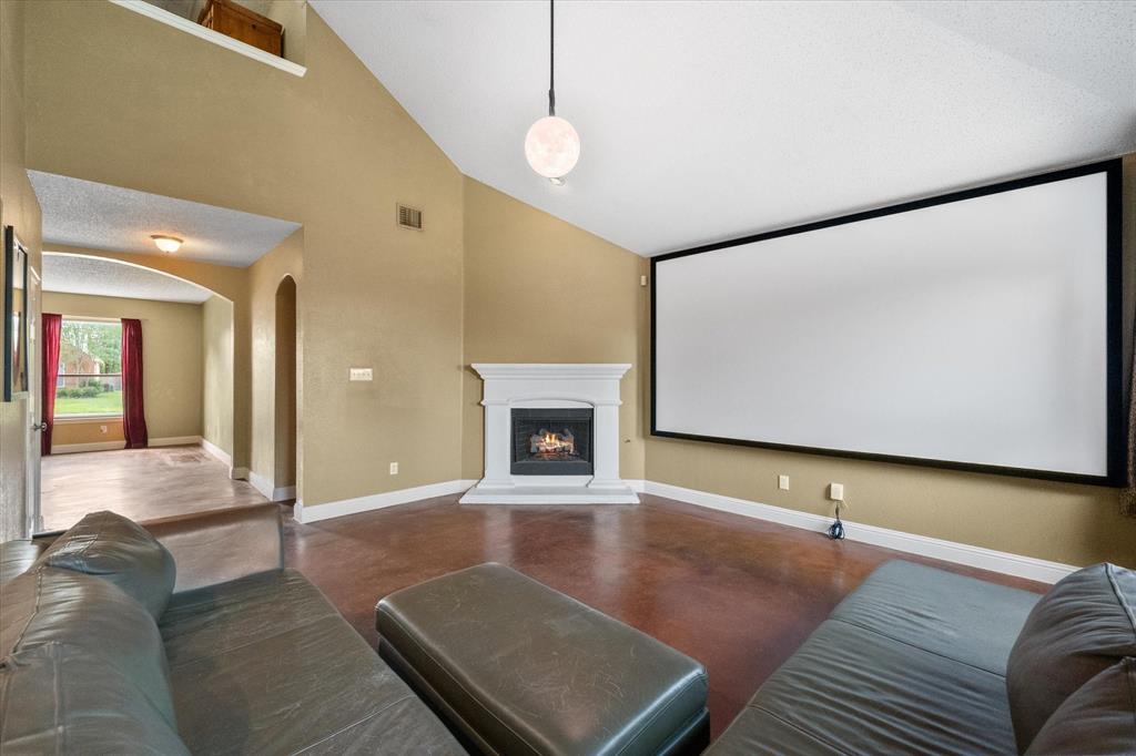 1305 Liverpool Lane Mansfield, TX 76063 - Photo 13 of 40 Living area featuring vaulted ceilings, a fireplace with a white mantel, and a large projection screen