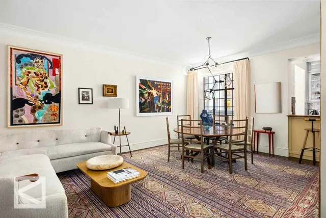 a living room with furniture a rug and wall paintings