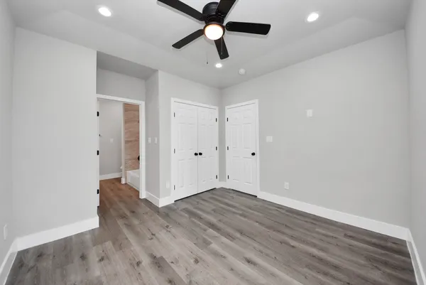 an empty room with wooden floor and ceiling fan