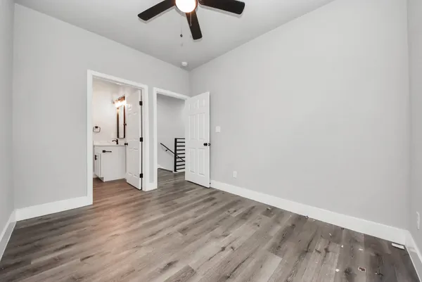 an empty room with wooden floor ceiling fan and windows