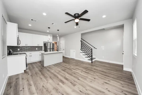 a kitchen with a refrigerator a microwave a sink and white cabinets
