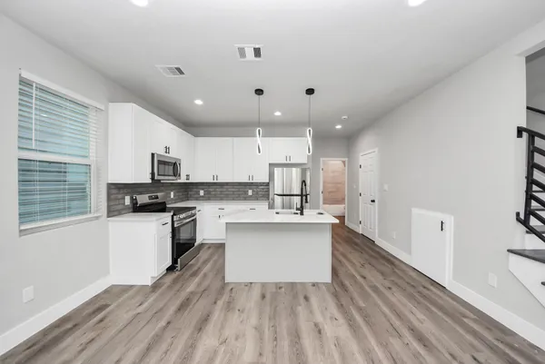 a kitchen that has a lot of cabinets a sink and wooden floor