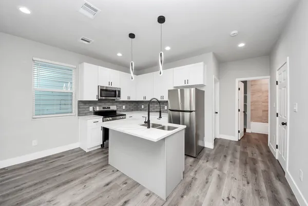 a kitchen with kitchen island stainless steel appliances a refrigerator sink and cabinets