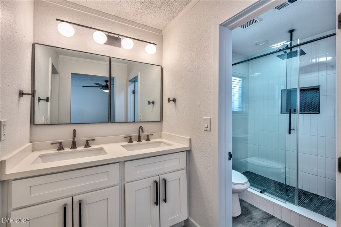 3017 Jamestown Way Las Vegas, NV 89102 - Photo 11 of 15 Bathroom with a textured wall, double vanity, a stall shower, ornamental molding, and a textured ceiling