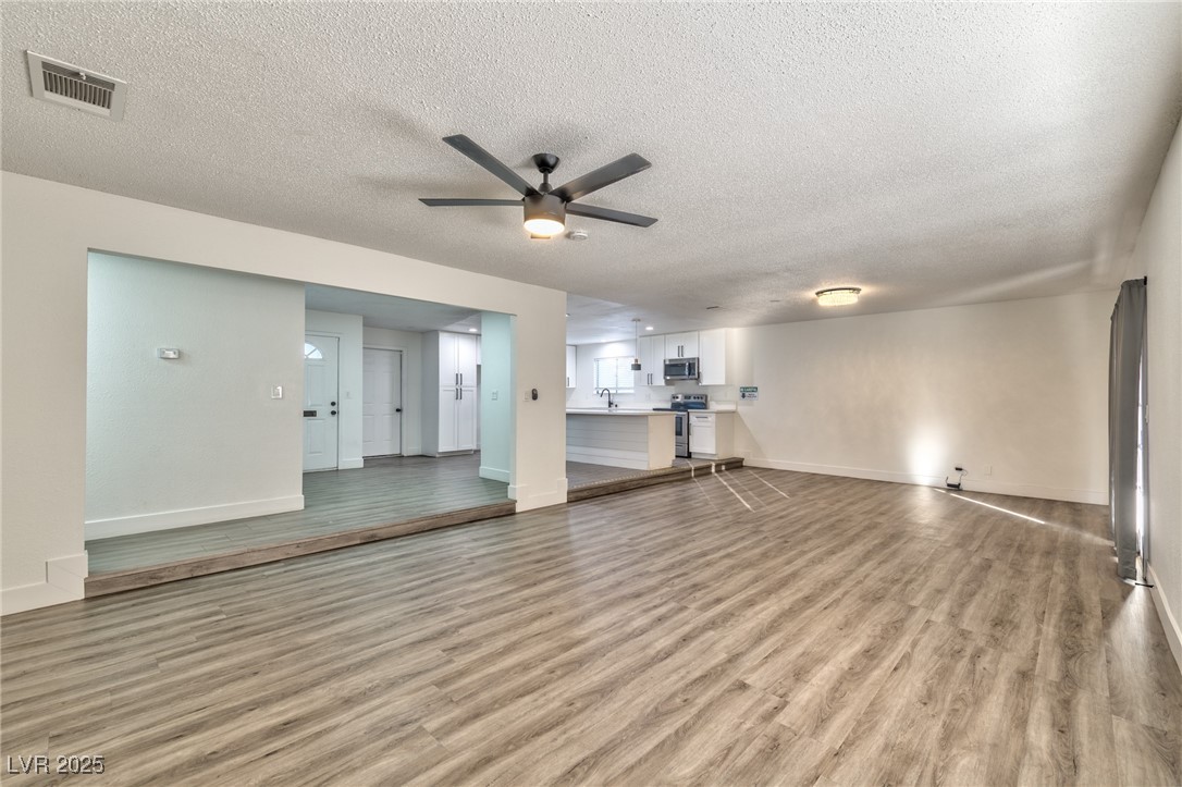 3017 Jamestown Way Las Vegas, NV 89102 - Photo 5 of 15 Unfurnished living room with a textured ceiling, light wood-style floors, and ceiling fan