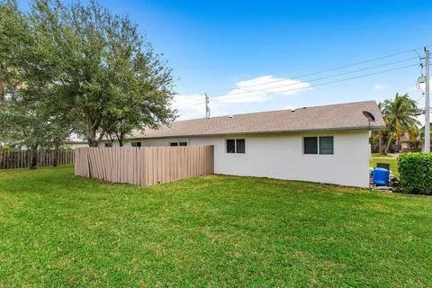 a view of a house with a yard and a large tree