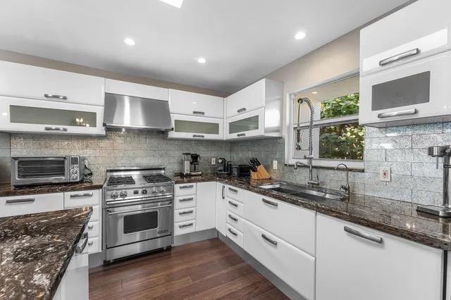 a kitchen with stainless steel appliances granite countertop a stove a sink and a microwave