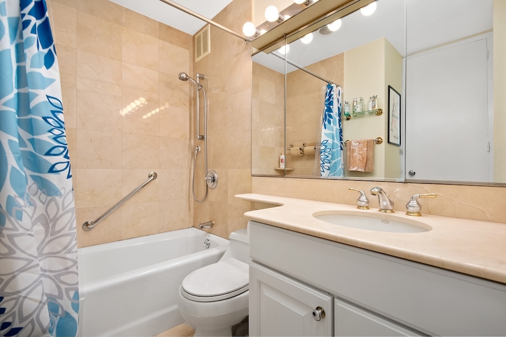1 East Scott Street, Unit 1003 Chicago, IL 60610 - Photo 10 of 11 a bathroom with a sink a toilet a mirror a bathtub and shower