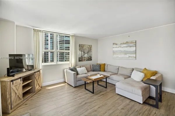 a living room with furniture a flat screen tv and wooden floor