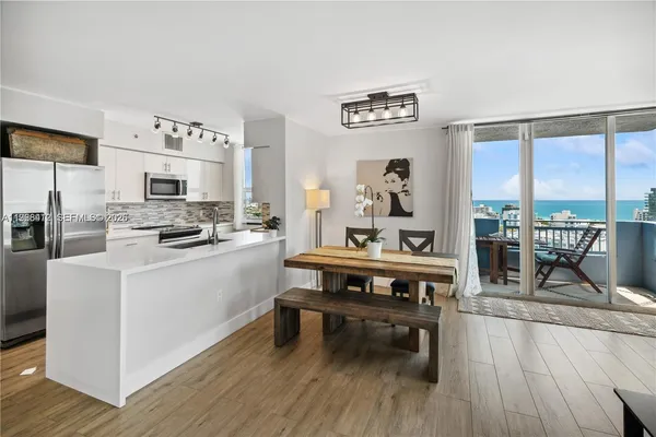 a living room with stainless steel appliances furniture wooden floor and a large window