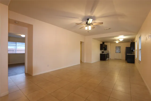 a view of a livingroom with a chandelier fan and kitchen view