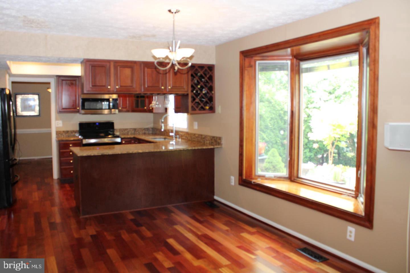 10918 Spyglass Hill Bowie, MD 20721 - Photo 6 of 9 a kitchen with stainless steel appliances granite countertop a refrigerator a sink dishwasher a stove and a dining table with wooden floor