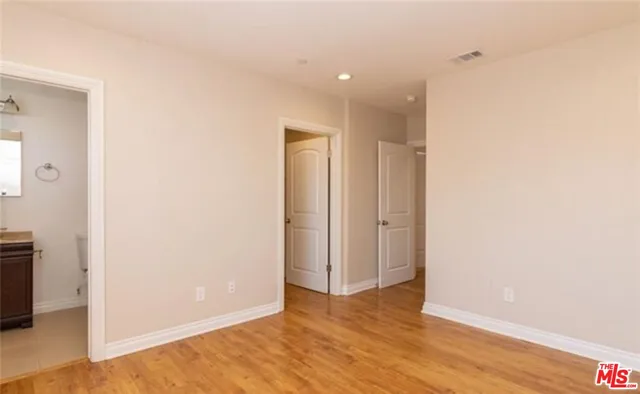 a view of an empty room with wooden floor and closet