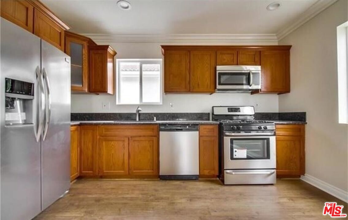 1203 1/2 South Catalina Street Los Angeles, CA 90006 - Photo 7 of 11 a kitchen with stainless steel appliances granite countertop a stove a sink and a microwave