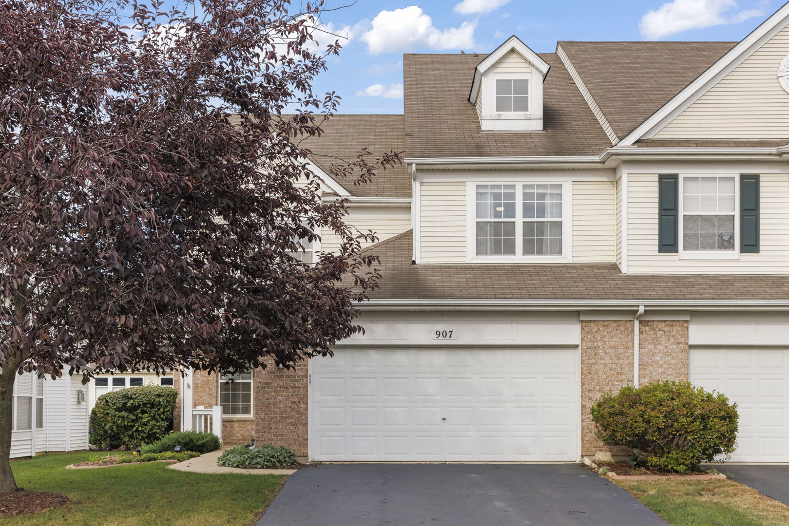a front view of a house with a garden and trees