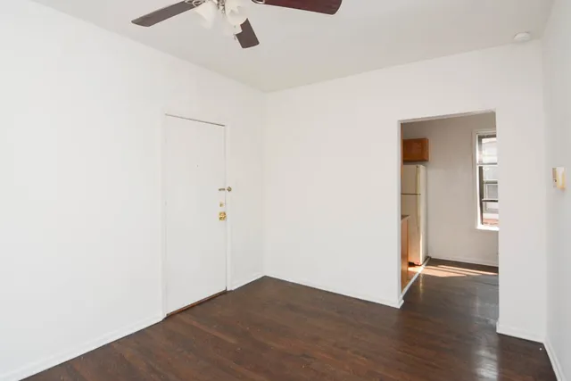 an empty room with wooden floor and a ceiling fan