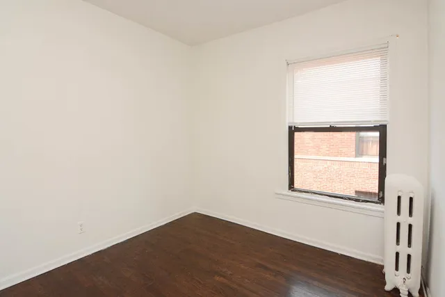 an empty room with wooden floor and a window
