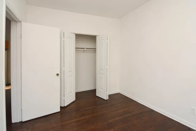 a view of an empty room with wooden floor and closet