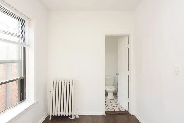 a view of a hallway with wooden floor and a bathroom