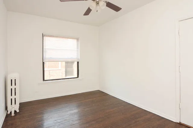 an empty room with a window and a ceiling fan