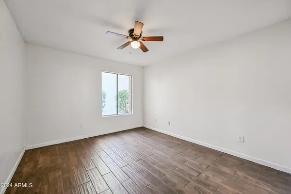 a view of empty room with wooden floor and fan
