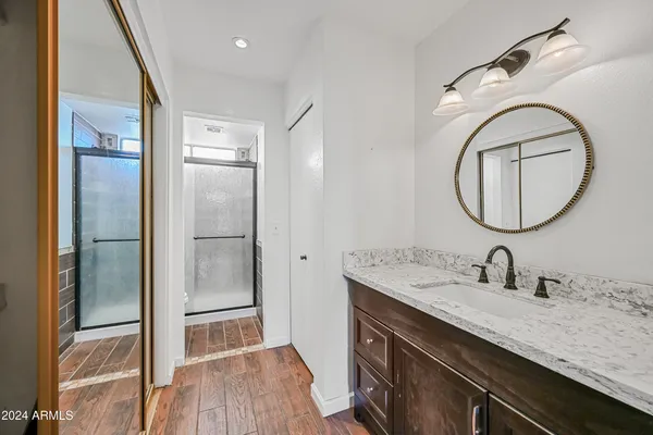 a bathroom with a granite countertop sink a mirror and a shower