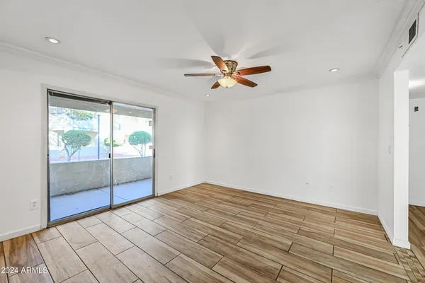 a view of empty room with wooden floor and fan
