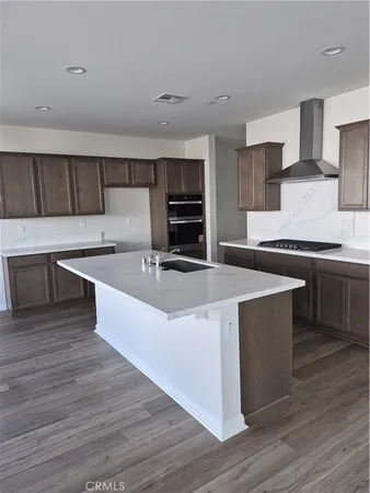 a large kitchen with stainless steel appliances a large counter top stove and cabinets