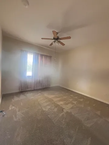 an empty room with windows and fan