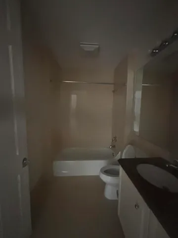 a bathroom with a granite countertop sink a toilet and shower