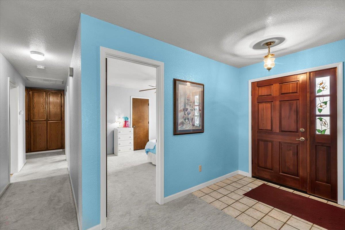 2136 Candy Cane Walk Manteca, CA 95336 - Photo 25 of 60 entrance foyer featuring a textured ceiling, light tile patterned flooring, and light carpet