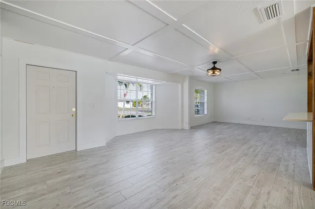a view of an empty room with a window and wooden floor