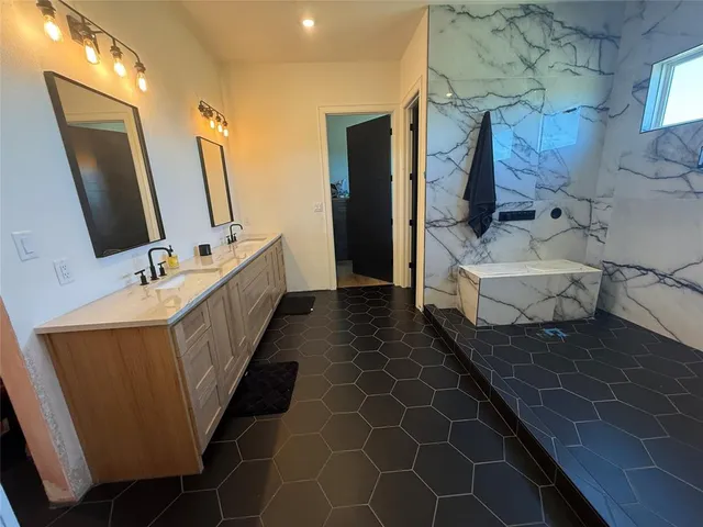 a bathroom with a double vanity sink a large mirror and a bathtub