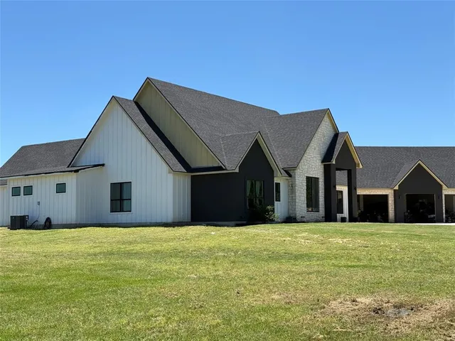 a front view of house with yard and trees in the background