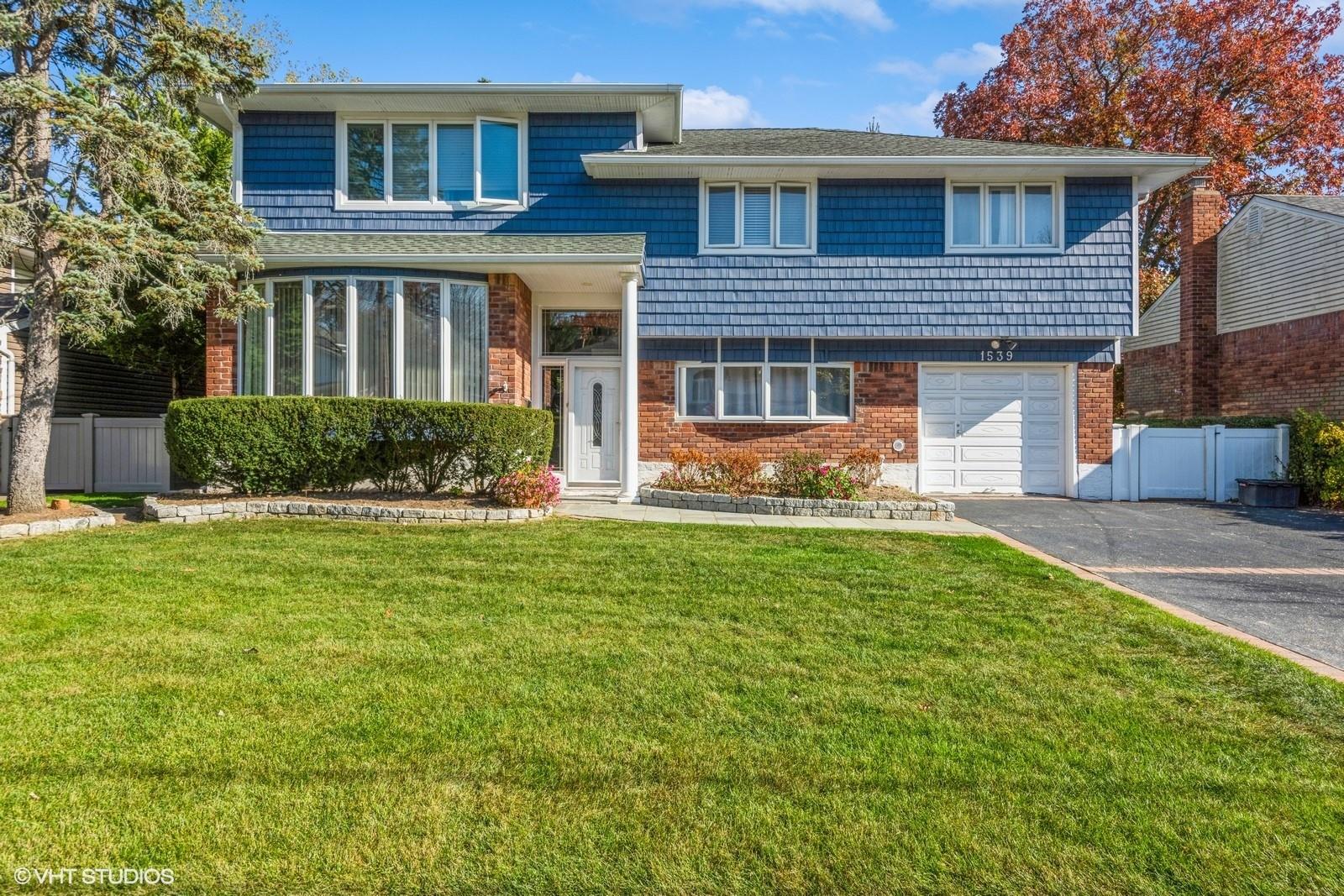 1539 Jennie Road Wantagh, NY 11793 - Photo 1 of 1 View of front of house featuring a garage, aphalt driveway, fence, a front yard, and brick siding