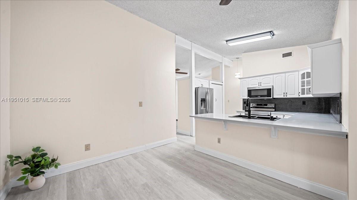 9798 Southwest 147th Place Miami, FL 33196 - Photo 4 of 17 a large white kitchen with stainless steel appliances a refrigerator a stove a microwave and white cabinets
