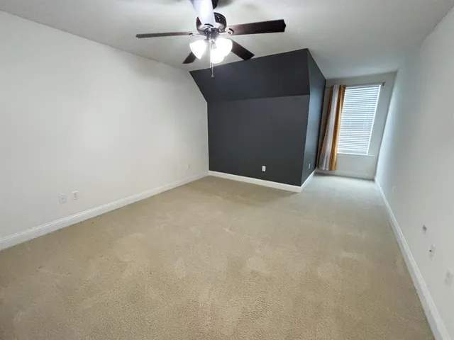 an empty room with a ceiling fan and a window