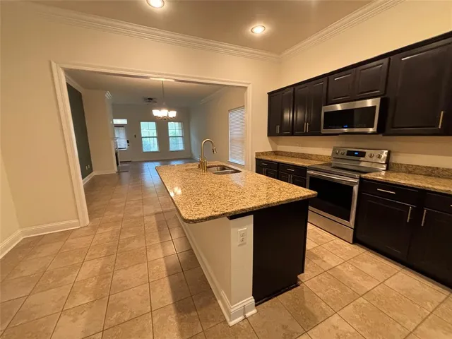 a kitchen with stainless steel appliances granite countertop a stove a sink and a microwave