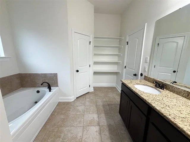 a bathroom with a granite countertop tub sink and mirror