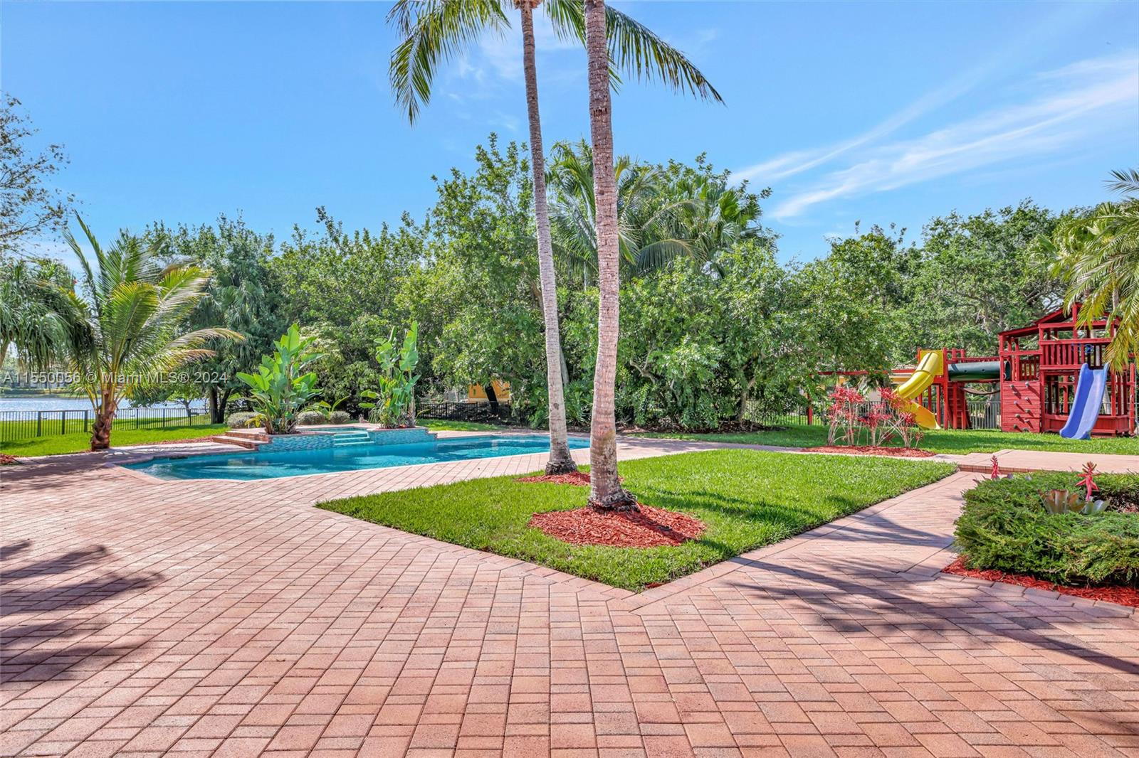 2725 Windmill Ranch Road Weston, FL 33331 - Photo 65 of 99 a view of a swimming pool with a yard and palm trees