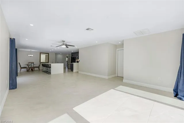 a living room with stainless steel appliances kitchen island a table and chairs in it