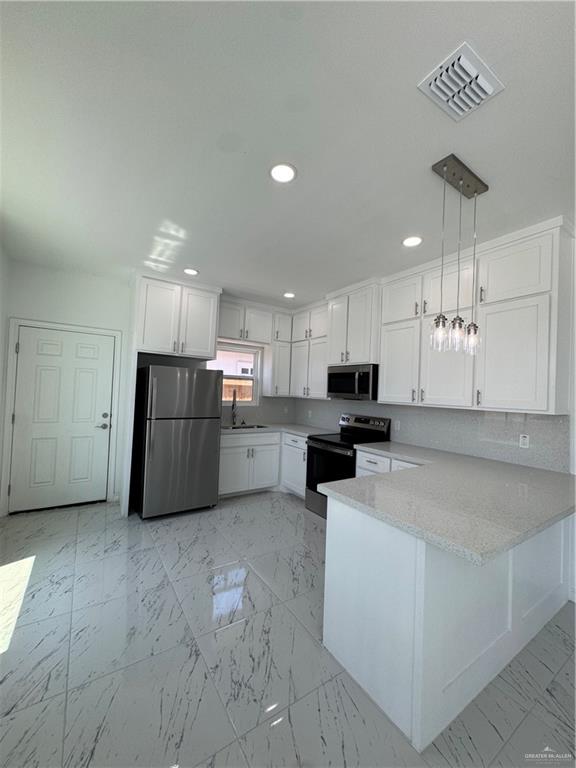 2101 Selena Street, Unit 1 Mission, TX 78572 - Photo 5 of 18 a large white kitchen with a refrigerator a stove top oven a sink and cabinets