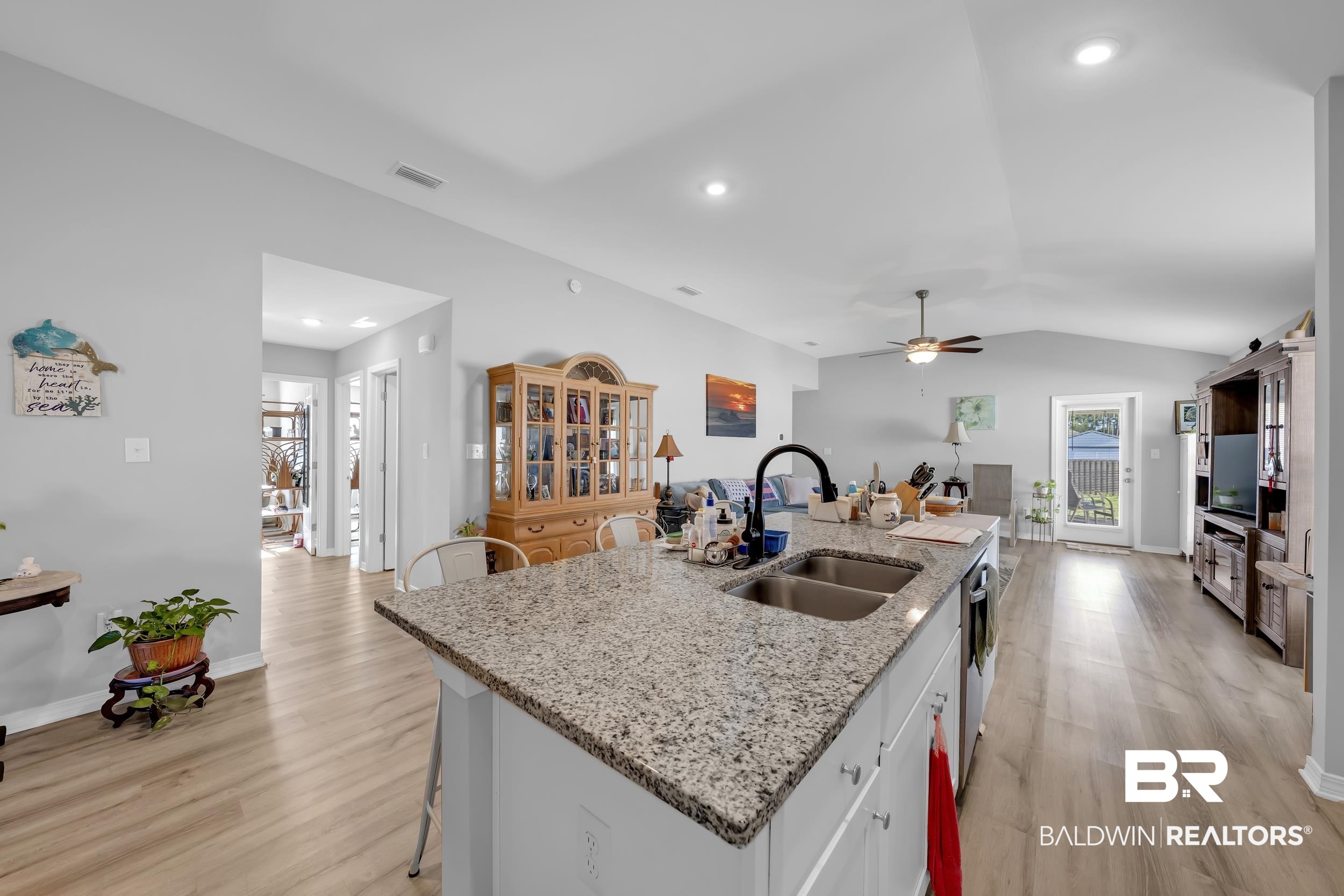 1228 Caper Avenue Foley, AL 36535 - Photo 7 of 54 Kitchen island featuring a double-basin sink, black gooseneck faucet, and light-toned granite countertop