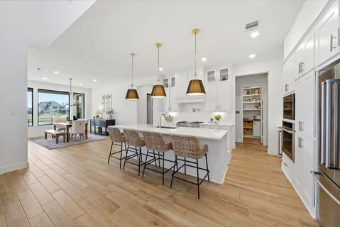 a kitchen with stainless steel appliances granite countertop a sink a stove a refrigerator and island with wooden floor